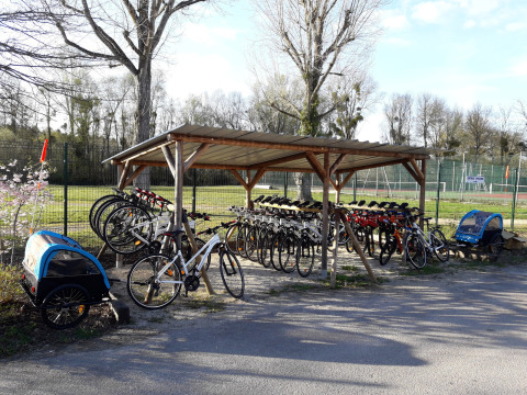 Cobertizo para bicicletas con bicicletas y remolques de alquiler en Huttopia Les Châteaux, Centro-Valle del Loira, Francia.