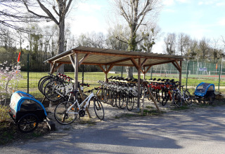 Cykelskur med udlejningscykler og cykelanhængere ved Huttopia Les Châteaux feriepark i Centre-Val de Loire, Frankrig.
