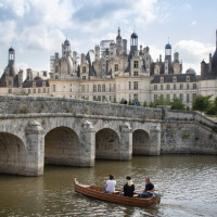 Personas remando en un bote frente al Castillo de Chambord cerca de Bracieux, Centro-Valle de Loira, Francia.