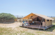 Safaritent Bungalow Classic bij Huttopia Côte Sauvage in Frankrijk met terras, persoon en natuurlijke omgeving.
