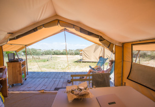 Vista desde un bungalow en tienda safari en Huttopia Côte Sauvage, con una persona relajándose afuera.