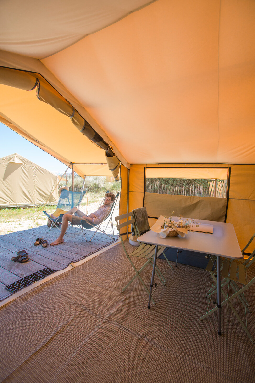Interieur van een safaritent Bungalow Classic bij Huttopia Côte Sauvage, Frankrijk, met een relaxte persoon.