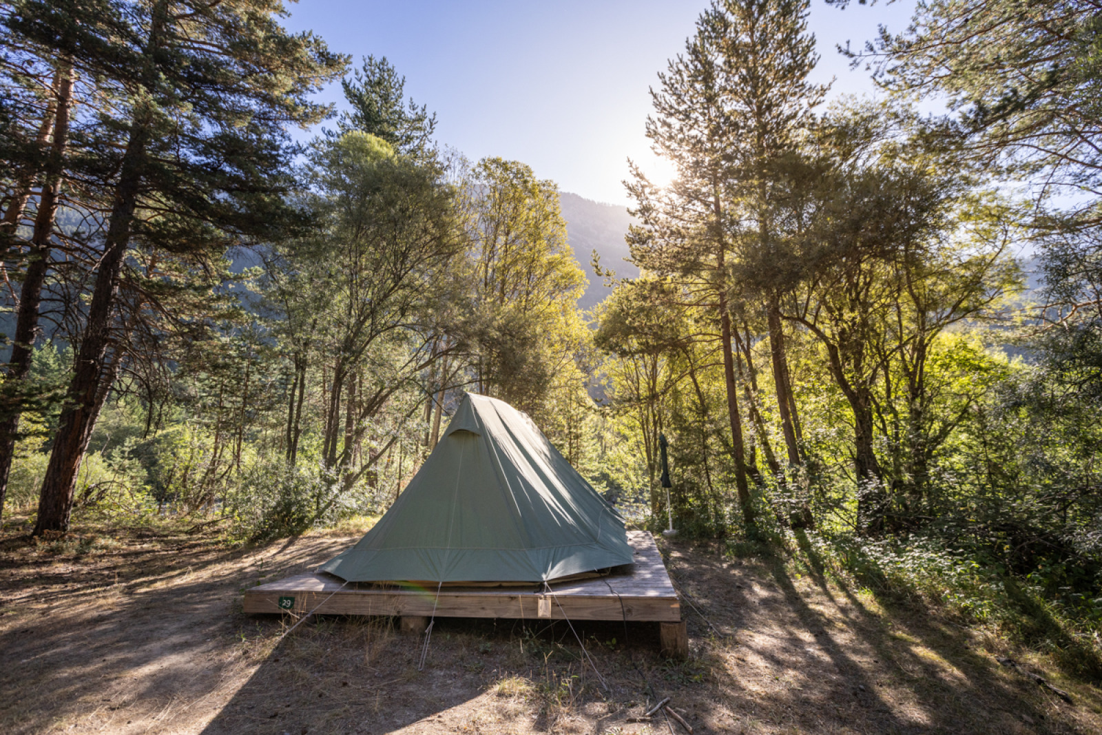 De Bonaventure tipi-tent op een houten platform in een zonnig bos bij Huttopia la Clarée, Frankrijk.