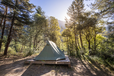 La tenda tipi Bonaventure su una piattaforma in legno nella foresta soleggiata di Huttopia la Clarée, Francia.