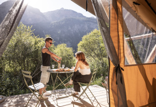 Koppel geniet van een maaltijd aan de Bungalow tent Classic safari tent bij Huttopia la Clarée in Frankrijk, bergzicht.