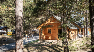 Udsigt over Chalet Montana Vista, en træhytte i skoven med folk, der går og biler parkeret udenfor.