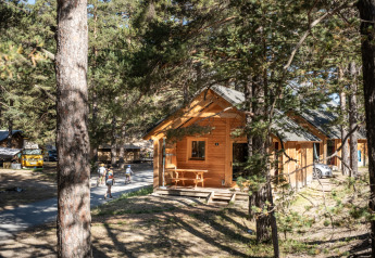 Uitzicht op Chalet Montana Vista, een houten blokhut tussen de bomen met wandelaars en geparkeerde auto's.