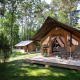 Safari telt kaldet Canadienne Tent placeret i en skov med træterrasse og campingmøbler ved indgangen.