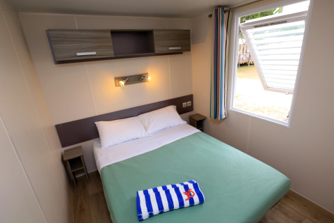 Acogedor dormitorio con cama doble en casa móvil de Camping La Pinède, Excenevex, Francia.