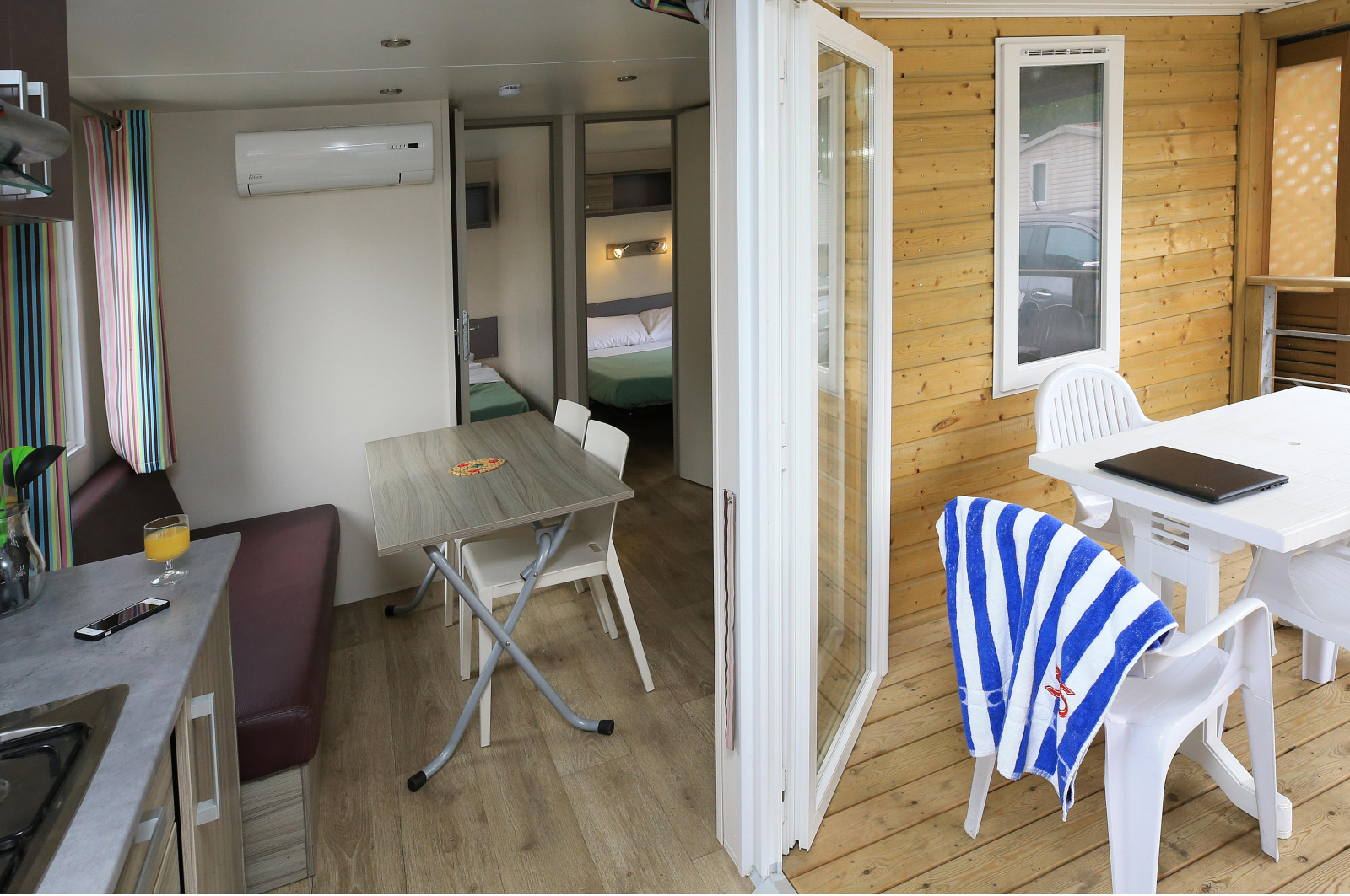 Binnen- en buitenaanzicht van een stacaravan op Camping La Pinède - Excenevex, Frankrijk, met eethoek en terras.