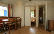 Interno di una casa mobile al Camping La Pinède di Excenevex, Francia, con zona pranzo e camera da letto.
