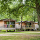 Træhytter ved navn Chalet Evasion blandt grønne træer med terrasser og havemøbler i skovområde.