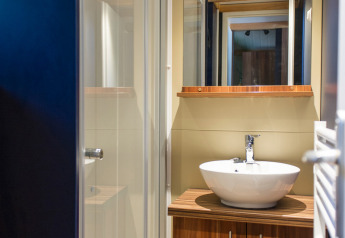 Moderne badkamer in Chalet Evasion bij Huttopia Les Châteaux in Frankrijk, met houten meubel en spiegel.
