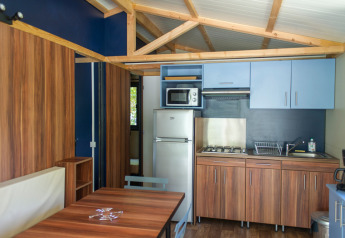 Cucinotto moderno e zona pranzo al Chalet Evasion, Huttopia Les Châteaux, Francia, con arredo in legno.