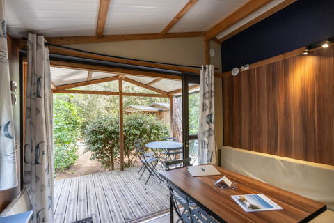 Interior del Chalet Evasion en Huttopia Les Châteaux, Francia, con vista a la terraza y muebles de jardín.
