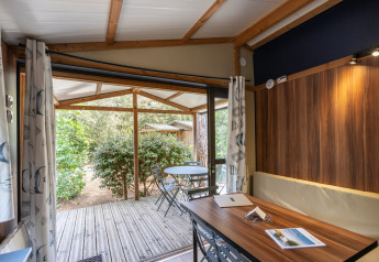Binnenaanzicht van Chalet Evasion bij Huttopia Les Châteaux, Frankrijk, met terras en tuinmeubilair.
