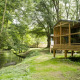 Træhytte ved floden i skovområde, Chalet Evasion Bord de Rivière, med terrasse og udsigt til naturen.