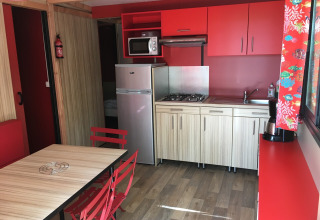 Moderne køkken i Chalet Evasion Bord de Rivière på Huttopia Les Châteaux i Frankrig, med røde nuancer.