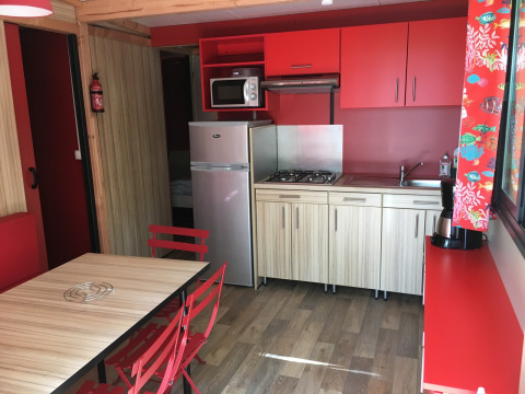 Modern kitchen in Chalet Evasion Bord de Rivière at Huttopia Les Châteaux, France, featuring bold red decor.
