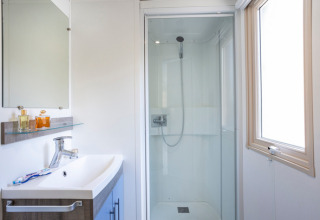 Moderne badkamer met douche, wastafel en spiegel in Mobile Home Vancouver bij Huttopia Les Châteaux, Frankrijk.