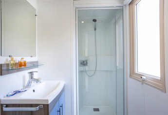 Modern bathroom with shower, sink, and mirror inside Mobile home Vancouver at Huttopia Les Châteaux, France.