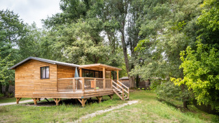 Chalet Portland Riverside, een houten chalet met terras midden in het groen en omgeven door hoge bomen.