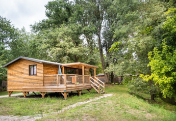Chalet Portland Riverside, una baita di legno con veranda immersa tra alberi verdi in una zona tranquilla.