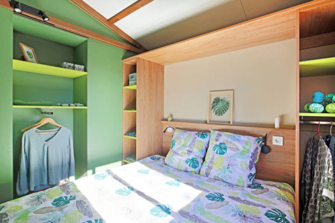 Camera da letto presso Chalet Portland Riverside a Huttopia Les Châteaux, Francia, con toni verdi e arredamento moderno.