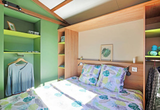 Dormitorio del Chalet Portland Riverside en Huttopia Les Châteaux, Francia, con tonos verdes y decoración moderna.