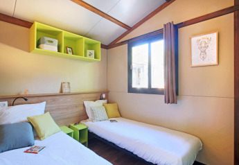 Gezellige slaapkamer met twee eenpersoonsbedden in Chalet Portland Riverside bij Huttopia Les Châteaux, Frankrijk.