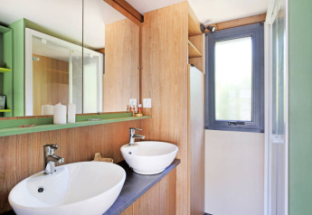 Moderne badeværelse med dobbelt håndvask, store spejle og trædetaljer i Chalet Portland Riverside, Frankrig.