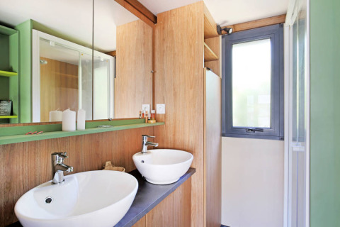 Baño moderno con doble lavabo, detalles de madera y gran espejo en el Chalet Portland Riverside, Francia.