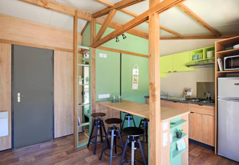Innenraum des Chalet Portland Riverside bei Huttopia Les Châteaux mit moderner Küche und Essbereich.