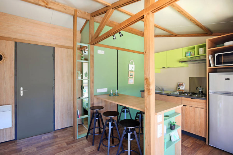 Interior del Chalet Portland Riverside en Huttopia Les Châteaux con cocina moderna y área de comedor.