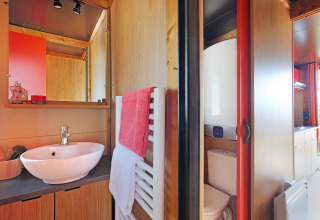 Moderne badkamer in een hut bij Roulotte, Huttopia Les Châteaux, met wastafel, spiegel en toilet.
