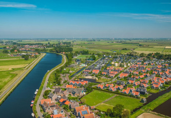 Vista aérea de la Tiny House en De Rijp, Países Bajos, con tejados rojos, canales y campos verdes.