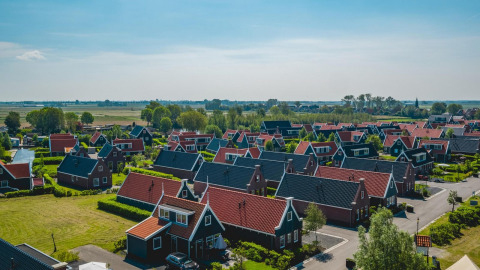 Uitzicht op Tiny House-lodges bij De Rijp in Nederland, met rode daken en groene velden rondom de huisjes.