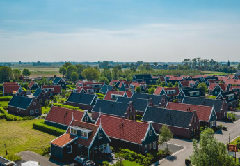 Udsigt over charmerende småhuse med røde tage på De Rijp-lodgen i Holland, omgivet af grønne marker.