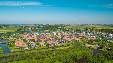 Aerial view of small houses with red roofs and surrounding canals at Tiny House in De Rijp, Netherlands.