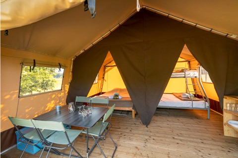 Intérieur de la Classic Tent au Camping de Paris, avec table à manger, chaises et lits pour le glamping.