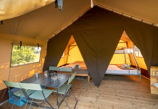 Intérieur de la Classic Tent au Camping de Paris, avec table à manger, chaises et lits pour le glamping.