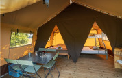 Interior de la Classic Tent en Camping de Paris, con mesa de comedor, sillas y camas para glamping cómodo.