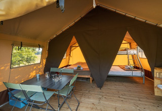 Interior de la Classic Tent en Camping de Paris, con mesa de comedor, sillas y camas para glamping cómodo.