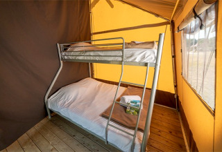 Lits superposés dans l’intérieur chaleureux d’une tente safari classique au Camping de Paris, France.