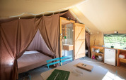 Interior de tienda safari con cama, baño y cocina en Tent Sweet del Camping de Paris, Francia.