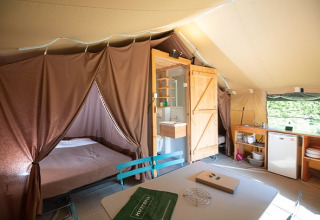Interior de tienda safari con cama, baño y cocina en Tent Sweet del Camping de Paris, Francia.