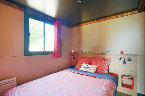 Camera da letto in una roulotte al Camping de Paris, Francia, con biancheria colorata e atmosfera accogliente.