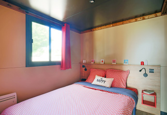 Camera da letto in una roulotte al Camping de Paris, Francia, con biancheria colorata e atmosfera accogliente.