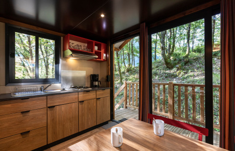 Interieur van keuken en eettafel in een zigeunerwagen op Camping de Paris met zicht op het bos.
