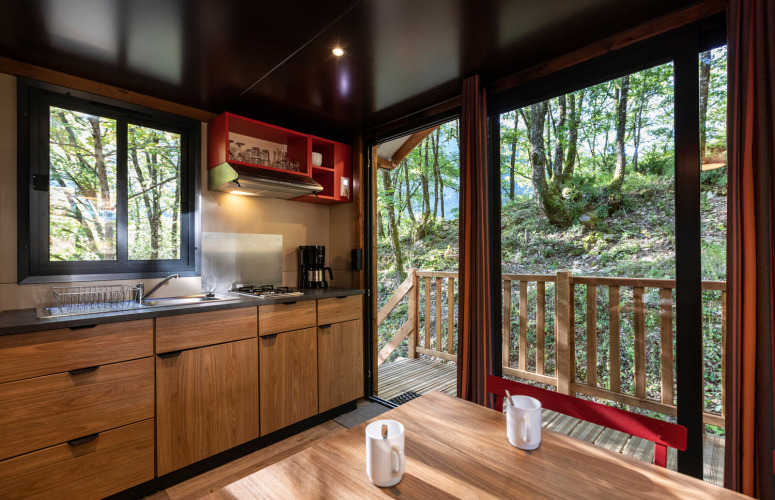 Vista interior de una cocina y mesa en una caravana gitana en Camping de Paris con vistas al bosque.
